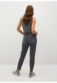 Jeans grises de talle alto con un diseño de pierna recta, bolsillos traseros y costuras sutiles, combinados con una camiseta de tirantes gris acanalada y zapatillas.