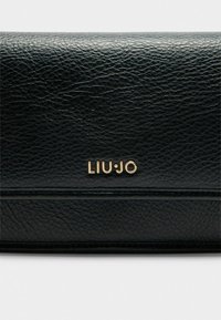 Sort læderbillede med tekstureret overflade, der har et guld "LIU·JO" logo og en subtil vandret sømdetalje.