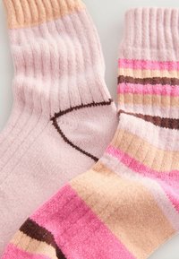Pink and striped socks; one solid pink, the other with pink, beige, and brown stripes; ribbed texture; soft material.