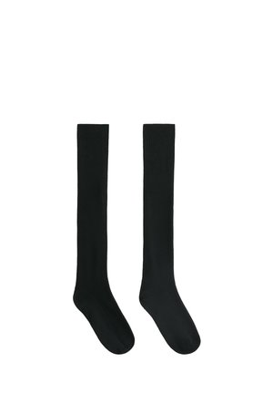 Paire de chaussettes noires unies montantes avec texture côtelée sur fond blanc.