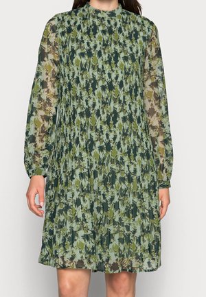 Vestido floral verde con mangas largas, cuello alto y textura plisada. Capa de tela transparente con tonos variados de verde y patrones marrones.