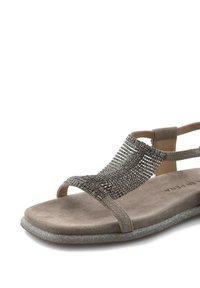 Graue Wildledersandale mit einem glitzernden Riemen über dem Obermaterial, offener Zehenpartie und einer flachen, strukturierten Sohle mit metallischem Glanz.