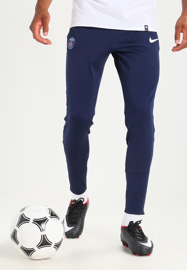 Pantalones deportivos de color marino con un diseño ajustado, que presentan un logo de PSG en el muslo y el swoosh blanco de Nike. Llevados con botas de fútbol negras y rojas.