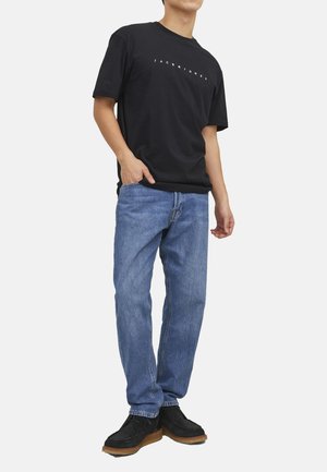 Zwarte t-shirt met het 'JACK & JONES' logo, blauwe denim jeans en zwarte schoenen. De t-shirt heeft een ronde hals, de jeans hebben een klassieke rechte pasvorm.