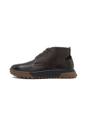 Bottines en cuir marron avec une finition texturée, dotées d'un bout arrondi, de six œillets et d'une semelle en caoutchouc marron robuste avec un motif en zigzag.