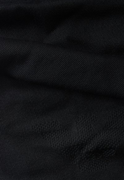 Gros plan d'un tissu noir texturé avec un motif brodé subtil créant un motif en relief sur la surface.