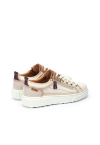 Zapatillas blancas con una suela gruesa, que presentan una combinación de texturas lisas y de ante, acentos en tonos rosa y púrpura apagados, y cremalleras laterales.