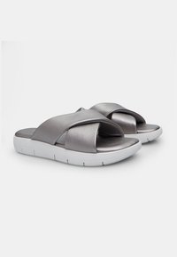 Sandale metalice argintii, cu curele încrucișate, talpă căptușită și talpă din cauciuc alb, având o textură netedă și un design minim.