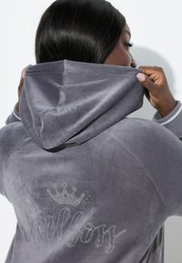 Szara welurowa bluza z kapturem z koroną i napisem „girlboss” wykonanym z kryształków, z kapturem regulowanym sznurkiem i subtelnymi prążkowymi mankietami. Gładka faktura.
