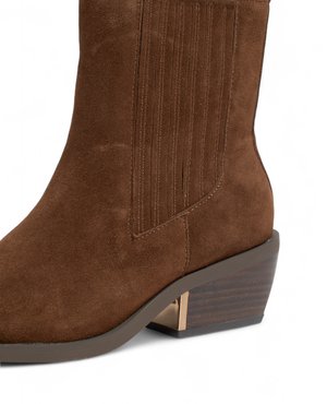 Stivaletto in suede marrone con cuciture verticali, punta quadrata e un tacco impilato moderato con un accento metallico.