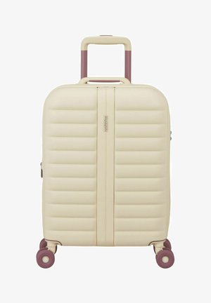 Maleta rígida beige con diseño acolchado vertical, asa retráctil y cuatro ruedas giratorias moradas, marca American Tourister.