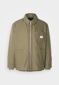 Olive green jacket, zip closure, ribbed collar, two front pockets, left chest pocket with logo patch, durable fabric, straight cut.