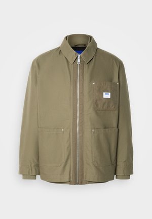 Olive zöld dzseki, cipzáros záródás, bordás gallér, két elülső zseb, bal melletti zseb logós címkével, tartós anyag, egyenes szabás.