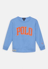 Vaalean sininen pitkähihaisten crewneck-huppari, jossa on oranssi "POLO" -teksti rinnan kohdalla, pieni punainen logo vasemmassa hihassa ja kangastarrat helman lähellä.