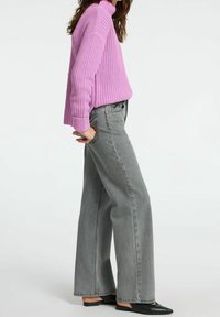 Pull en maille violet clair avec texture côtelée, associé à un jean gris à jambes larges taille haute et des ballerines noires à bouts pointus.