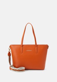 Orangefarbene Leder-Umhängetasche mit zwei Griffen und einem abnehmbaren Schultergurt, der ein Logo aufweist. Glatte Textur und minimalistisches Design, Logo mit goldenen Akzenten.