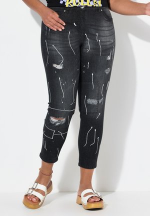 Zwarte denim jeans met witte verfspatten en versleten details, met een slim fit en een verkorte lengte. Witte stiksels en zakken.