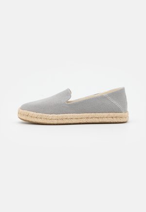 Grå slip-on espadrille med vævet jutesål og lærredsoverdel, vist i siden mod hvid baggrund.