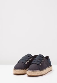 Námořnické plátěné espadrilky s kulatými špičkami, šněrovacím designem, juty rope podrážkami a zlatými očka, s malým logem jako akcentem.