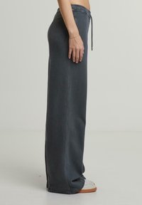 Zachte, donkergrijze loungebroek met touwtrekkoord. Heeft een relaxte pasvorm, rechte pijpen en subtiele stiksels.