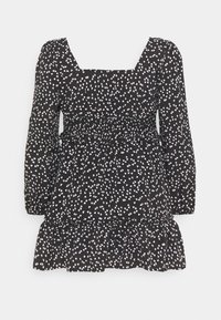 Svart klänning med långa ärmar, fyrkantig halsringning och rynkad midja. Har ett vitt hjärtformat mönster och volangkant. Mjuk tygtextur.