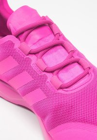 Baskets de sport roses avec tige en maille, superpositions texturées et lacets plats. Trois bandes verticales accentuent le côté. Semelle en caoutchouc lisse.