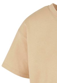 Vaaleanbeige lyhythihainen t-paita, jossa on pyöreä pääntie. Valmistettu pehmeästä puuvillasta, jossa on sileä pinta ja hienovaraisia ompeleet hihoissa.