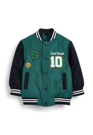 Grøn og sort varsityjakke med stribede manchetter og krave, patches med bogstavet "S", smiley, "Cool Dude" og nummer "10" foran.