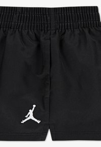 Μαύρο αθλητικό σορτς με ελαστική μέση, διακοσμημένο με λευκό κεντητό λογότυπο Jumpman στο κάτω αριστερό  μέρος. Λείο υλικό.
