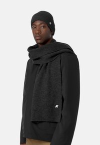 Set composto da berretto e sciarpa a maglia di colore grigio scuro, con una texture morbida, design a coste e un piccolo logo decorativo sulla sciarpa.