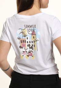 Weißes Baumwoll-T-Shirt mit einem grafischen Design von zwei Cartoonfiguren, Palmen und dem stilisierten Text "SUMMER LOVIN'."
