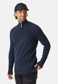 Mørkeblå ribbet sweater med høj krave og halv lynlås, der har et trælynlås træk og struktureret strikkemønster.
