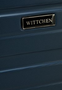 Námořnický tvrdý kufr s texturovaným povrchem, horizontálními drážkami a černou kovovou logoplátkou s nápisem "WITTCHEN" pro branding.