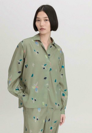 Lichtgroene blouse met een kraag, voorzien van een zachte textuur en een kleurrijk bloemenpatroon met blauwe, roze en witte accenten.