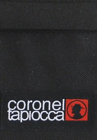 Parche textil negro con el logotipo bordado "coronel tapiocca" en blanco, con un acento rojo que representa una silueta.
