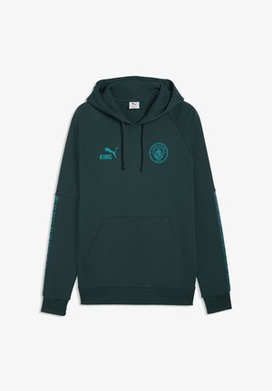 Sudadera con capucha verde oscuro con bolsilo frontal, logo de Puma en azul verdoso y texto "KING" en el pecho izquierdo, emblema del Manchester City en el pecho derecho y franjas estampadas en las mangas.