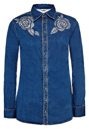 Chemise en denim bleu à manches longues avec boutons-pression à l'avant et motifs de roses blanches brodées sur les deux épaules.