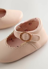 Helle rosa Leder-Babyschuhe mit rundem Zehenbereich, gewelltem Rand und einem seitlichen Schnallenverschluss. Innen mit floralen Mustern.