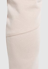 Hellbeige Jogginghosen aus einer weichen Baumwollmischung, mit geschwungenen Nähten und einer glatten Textur für Komfort und Flexibilität.