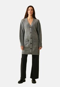 Grå stickad kofta med V-ringning, långa ärmar och två framfickor. Har knäppning med knappar samt ribbade muddar och fåll.