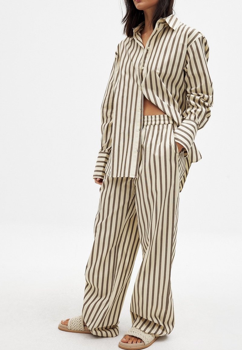 Striped cotton shirt and wide-leg pants in beige and brown, featuring a relaxed fit and an elastic waistband. Sandals with woven texture.