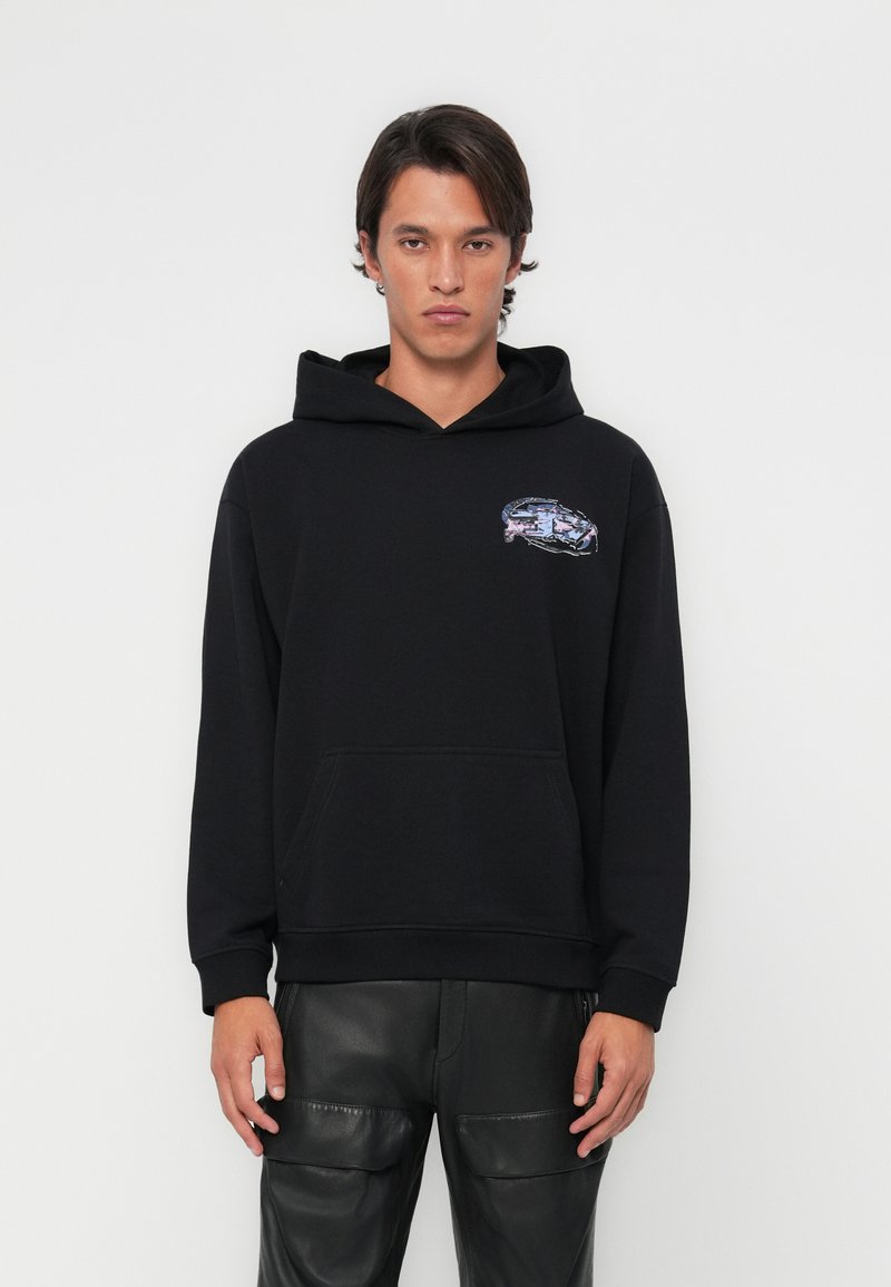 Sweatshirt noir avec capuche, poche frontale et un graphique coloré sur le côté gauche de la poitrine. Le tissu paraît doux avec une coupe décontractée.
