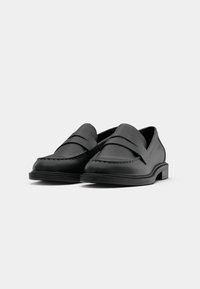 Black leather loafers featuring a moccasin-style design, stitched details, and a smooth finish. Flat rubber soles provide traction and comfort.