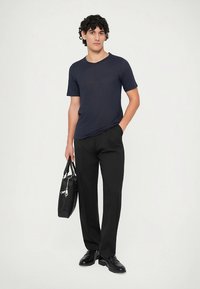 Marinblå t-shirt med rund hals och korta ärmar; svarta skräddarsydda byxor; svart läderväska med silverdetaljer; stylad med svarta skor.