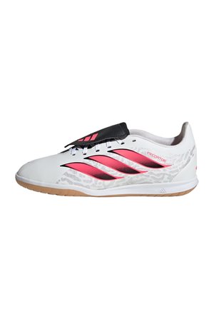 Zapatilla deportiva Adidas Predator blanca y rosa con cubierta negra para los cordones y suela de goma, mostrada de perfil sobre fondo blanco.