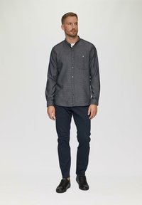 Grijs geruit overhemd met een kraag, enkel borstzakje, gecombineerd met marineblauwe slim-fit broeken en zwarte sneakers.