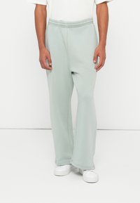 Helle grüne Sweatpants mit elastischem Bund, geraden Beinen und weichem Material, kombiniert mit weißen Sneakers.