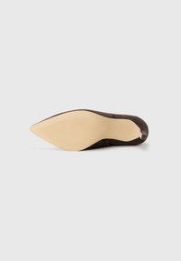 Zapato de tacón alto de ante marrón con punta afilada, que presenta una suela beige lisa y líneas de tracción sutiles para un mejor agarre.