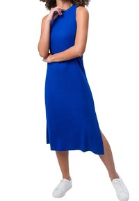 Sininen hihaton mekko suoralla leikkauksella, sivuhaalareilla ja pehmeällä kankaalla, yhdistettynä valkoisiin lenkkareihin rentoa ilmettä varten.