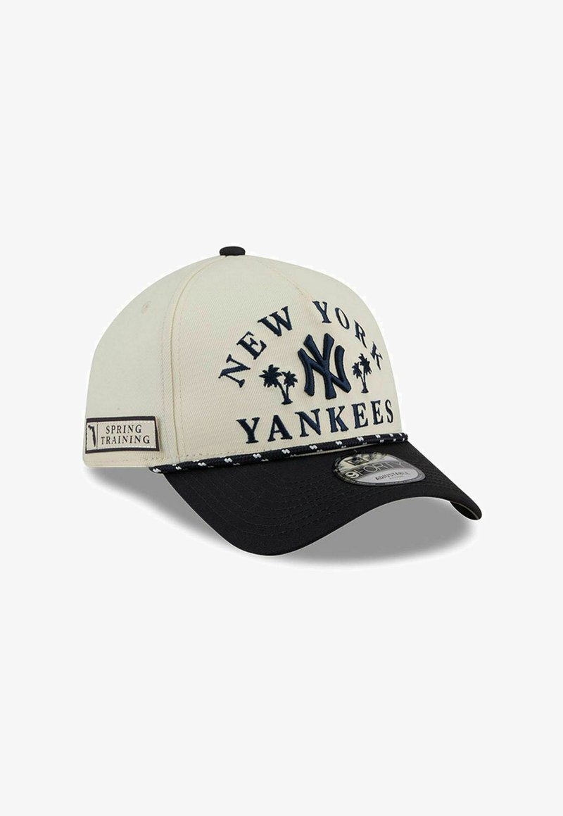 Beige ja musta New York Yankees -lippis, jossa on "Spring Training" -merkki, kirjailtu logo, palmupuut ja kaareva lippa.